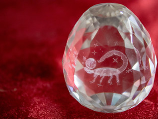 Scorpio and stars inside a transparent faceted abstract crystal on a bright red background.