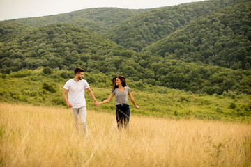 Fototapeta na wymiar Young couple in love walking through grass field