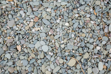 Top down view of pebbles smoothed rocks and stones on a beach with driftwood and other loose things, smooth natural beautiful imagery that's relaxing and gorgeous background