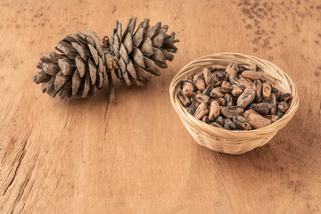 pine nuts, kernels and cone on a wooden table