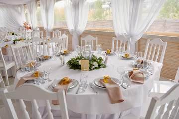 Table setting with blank guest card, plates with napkins and cutlery, copy space. Place setting at wedding reception. Round table served for banquet in restaurant
