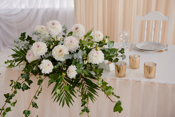 Lush floral arrangement of white chrysanthemum flowers on table. Luxury wedding decorations. Wedding presidium in restaurant, copy space. Banquet table for newlyweds