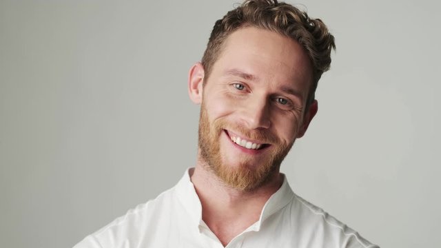 Handsome young positive cheerful man in white shirt isolated over white wall background says yes