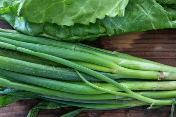 Fototapeta premium Closeup 4k footage of lots of fresh green vegetables against wooden background. Concept of healthy nutrition and organic food. Perfect background for vegetarian or vegan. Farming and agricultural