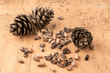 Fototapeta na wymiar pine nuts, kernels and cone on wooden table