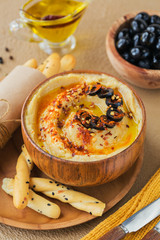A bowl of chickpeas homemade hummus with olive oil, black olives and crispbread