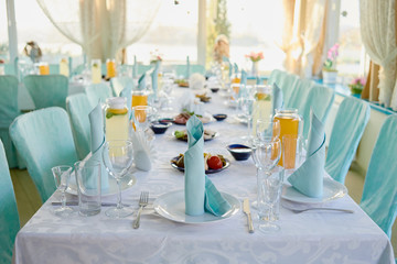 Table setting with sparkling wineglasses, plates with blue napkins and cutlery on table, copy space. Place set at wedding reception. Table served for wedding banquet in restaurant