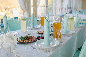 Table setting with sparkling wineglasses, plates with blue napkins and cutlery on table, copy space. Place set at wedding reception. Table served for wedding banquet in restaurant