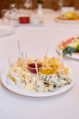 Cheese plate with honey on holiday dinner table, copy space. Wedding or birthday reception