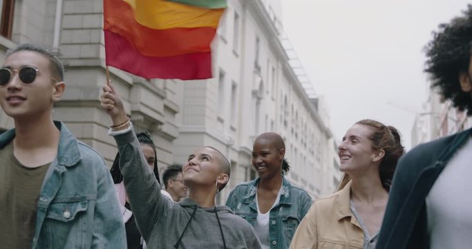 Happy young people with rainbow flag at gay parade