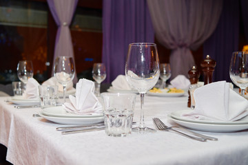 Table setting with sparkling wineglasses, plates with white napkins and cutlery on table, copy space. Place set at wedding reception. Table served for wedding banquet in restaurant