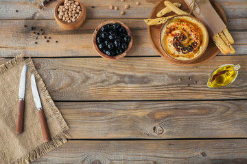 Healthy homemade creamy hummus with olive oil, black olives and crispbread. Healthy and diet food concept.