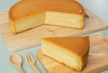 Caramel custard cake on wooden plate.  Slice a piece of cake on navy blue background.