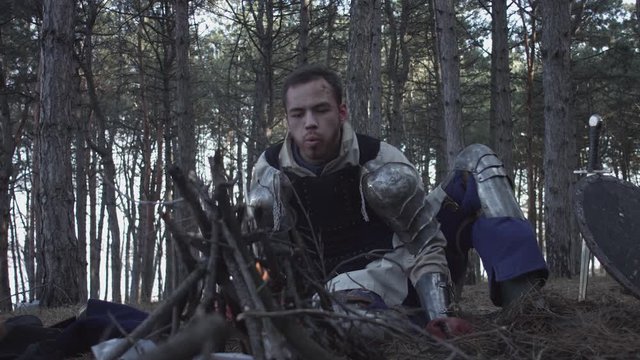 Two medieval knights sitting near bonfire and devide conquered or looted things