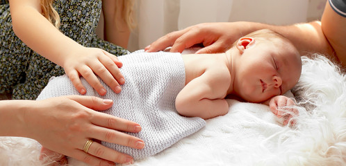 Hands of parents close-up and baby. A newborn boy was born in a happy family. Family concept.