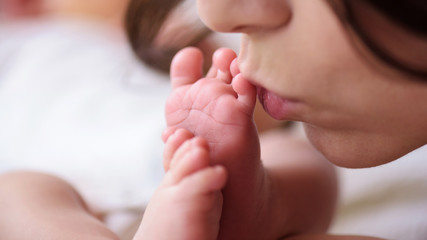 close-up. mom kisses the tender legs of her newborn baby