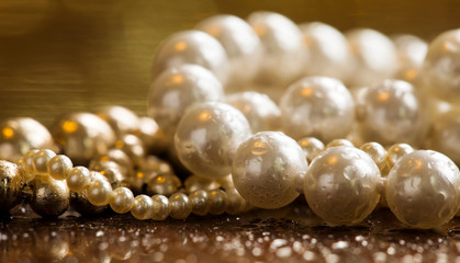 White pearls, female gift jewelry necklace on gold background, closeup