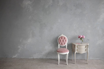 Minimalistic interior in the Baroque style. Vintage bedside table,a chair, a medallion with four...