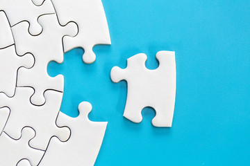 White jigsaw puzzle pieces on a blue background. Problem solving concepts. Texture photo with copy...