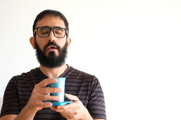 Bearded Jewish  holding a cup of wine for the Kidush on Shabbat. The man is standing in front of a white background and pronouncing the blessing