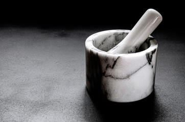 Marble mortar for grinding pepper stands on a black background