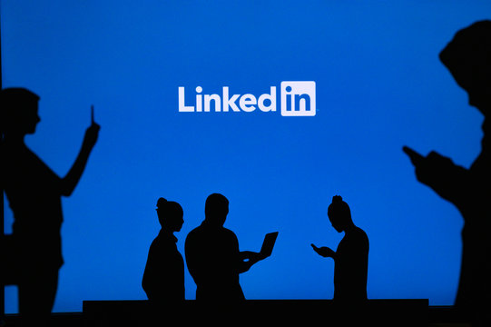 NEW YORK, USA, 25. MAY 2020: Linkedin business and employment-oriented online service Group of business people chat on mobile phone and laptop. Company logo on screen in background