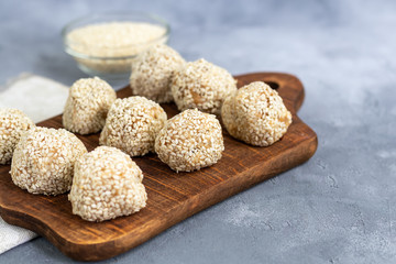 Energy bites without baking are made from ingredients - nuts, cocoa, chocolate, oats and sesame seeds. Located on a gray background.