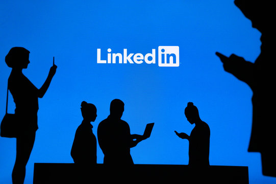 NEW YORK, USA, 25. MAY 2020: Linkedin business and employment-oriented online service Group of business people chat on mobile phone and laptop. Company logo on screen in background