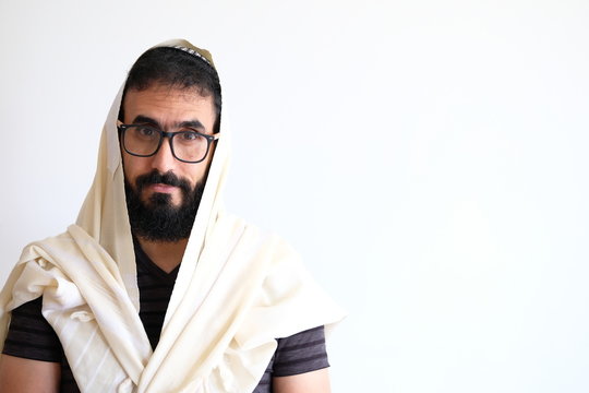 Bearded Jewish with a  Tallit (talis) . The man is standing in front of a white background and he is in the middle of a pray
