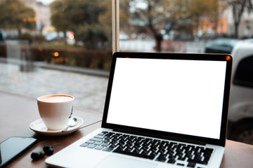 Fototapeta premium laptop with white screen in cafe table near window
