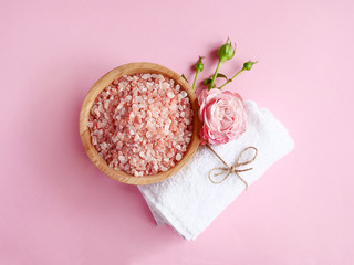 Fototapeta na wymiar Spa flatlay composition. Sea salt in wooden jar, towel, flower on pink background. Top view. Daily care concept, relax and rest, bath procedure