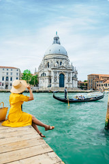 woman in yellow sundress sitting on pier with view of grand canal
