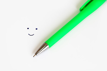 green stationery pen for writing and a painted cheerful smile