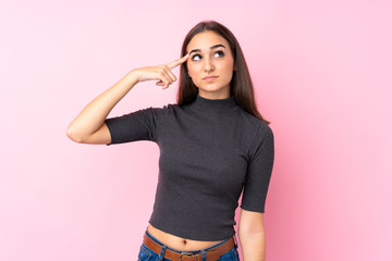 Young girl over isolated pink background making the gesture of madness putting finger on the head