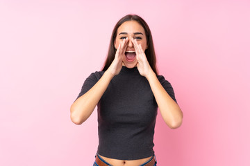 Young girl over isolated pink background shouting and announcing something