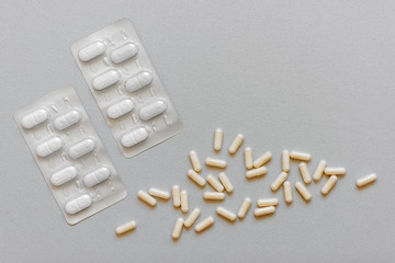 Antibiotics (prescription drug) lying together with probiotics on a gray background.