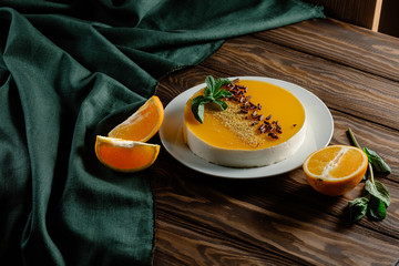 Orange cheesecake with a layer of jelly from an orange on top, garnished with mint, oranges,...