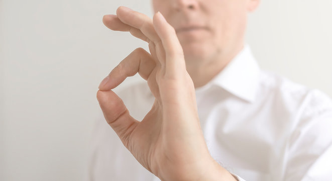 bright picture of male hand showing ok sign jesture in a white shirt on a white background. Everything will be OK concept