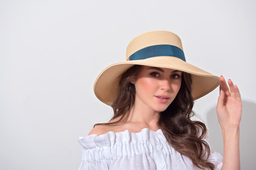 Portrait of cute girl with long brunette hair in a white dress over white wall