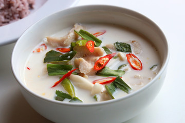 Close up Chicken in coconut milk soup, served in a white bowl Placed on a white table top