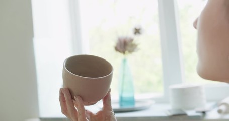 Female potter sitting and makes a cup. Woman making ceramic item. Pottery working, handmade and creative skills