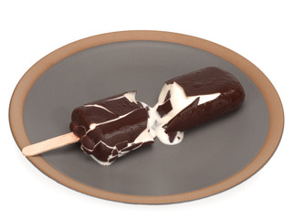 Melted Ice cream covered with chocolate, broken in a plate on a white background