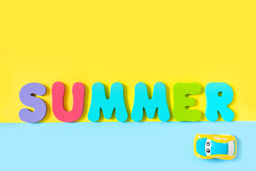 Model toy car and word SUMMER made of colorful letters on yellow background. Concept of travel and vacation. Top view, flat lay, copy space.