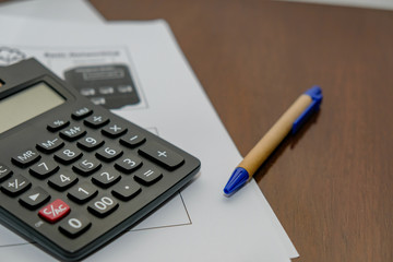 Calculator Documents with pen Resting on a wooden table