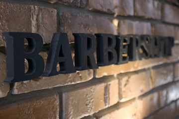 Barbershop inscription, text on a brick wall, close-up, black letters.