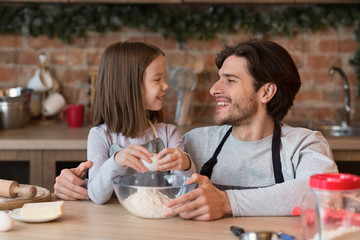 Obraz na płótnie Canvas Little girl and her dad baking together in kitchen, preparing dough