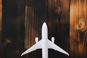 White model of passenger plane on old wooden background. Travel saving and planning concept - Top view.