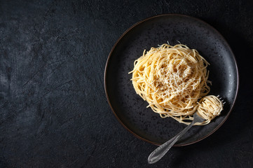 Cacio e Pepe - Italian Pasta with Cheese and Pepper on Black Plate on Dark Background. Top View Flat Lay. Copy Space
