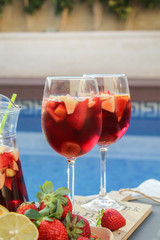 Spanish red wine (Sangria) with fruit. Strawberry, orange, Apple and banana slices. On a tray next to the pool