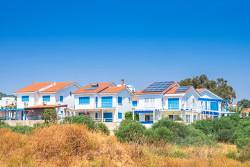 Fototapeta na wymiar Cyprus. Pissouri village. Apartments in village of Pissouri. Solar panels are installed on the roof of the houses. Renewable energy. Traveling to Cyprus. Pissouri holiday resort. Cyprus architecture